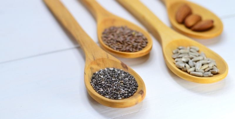 Grains and seeds sitting inside a wooden spoon.