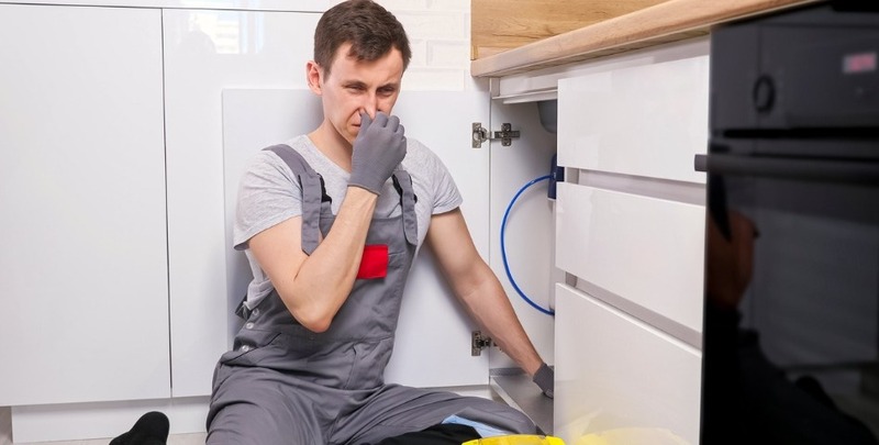 A plumber smells a gas leak as he's working
